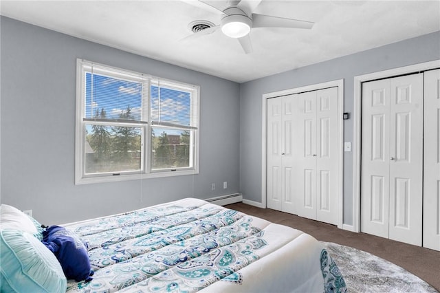 bedroom with baseboard heating, multiple closets, dark colored carpet, baseboards, and visible vents
