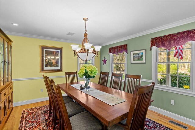 dining space with visible vents, light wood finished floors, baseboards, and a notable chandelier
