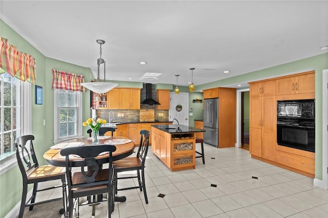 interior space featuring a sink, wall chimney exhaust hood, black appliances, and tasteful backsplash