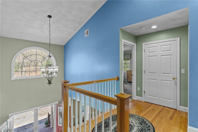 entryway with a chandelier, plenty of natural light, light wood-style flooring, and visible vents