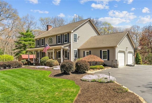 view of front facade featuring a garage, a chimney, driveway, and a front yard