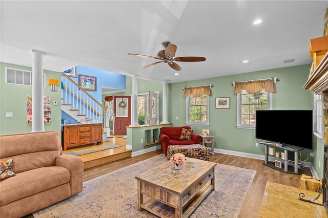 living area with ceiling fan, stairs, decorative columns, wood finished floors, and visible vents