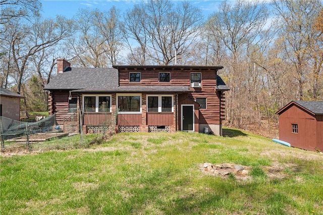 back of property with log siding, a storage shed, a chimney, an outdoor structure, and a yard
