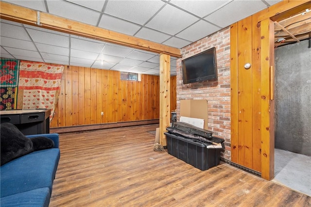 interior space with wood walls, a baseboard heating unit, a paneled ceiling, and wood finished floors