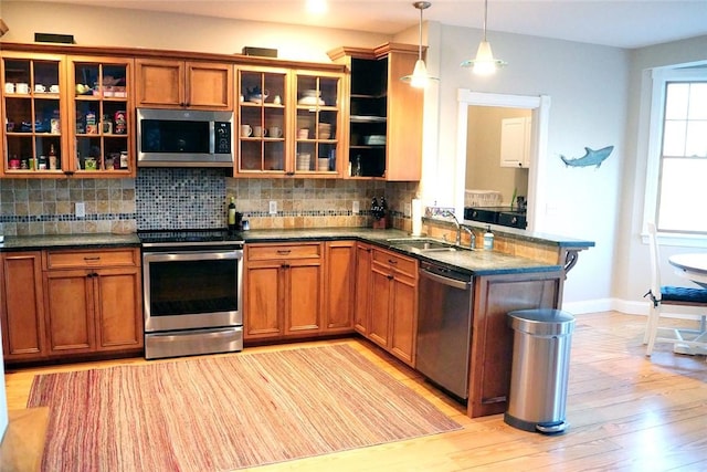 kitchen featuring appliances with stainless steel finishes, brown cabinetry, a sink, and tasteful backsplash