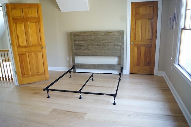 bedroom with a skylight, baseboards, and wood finished floors