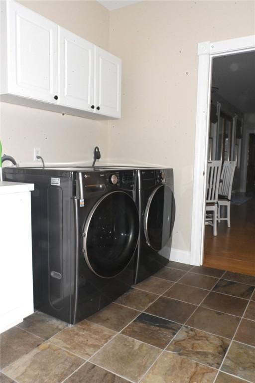 washroom with cabinet space, baseboards, and washing machine and dryer
