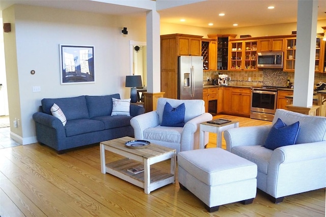 living area with light wood-type flooring, recessed lighting, and baseboards