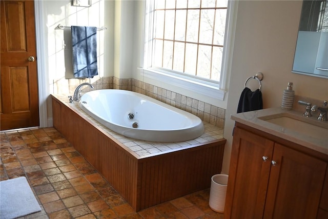 full bathroom featuring a tub with jets, stone finish flooring, and vanity