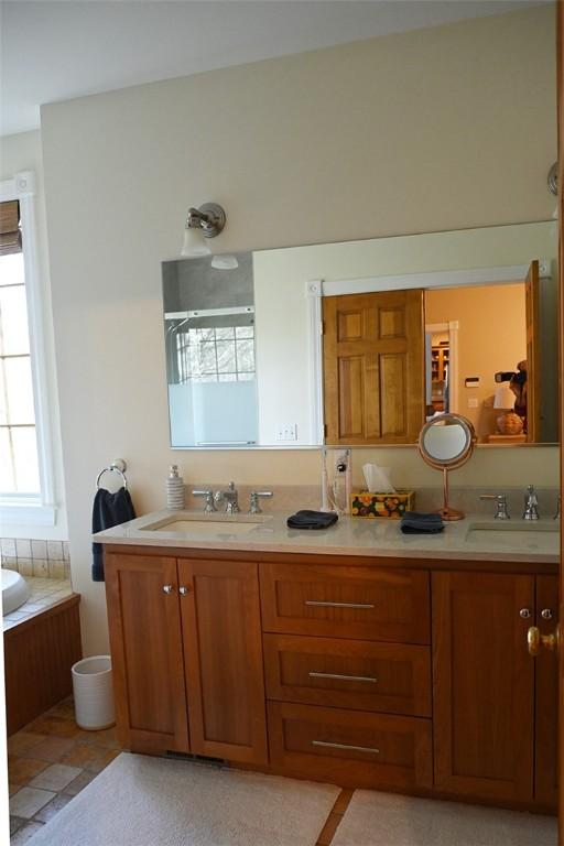 bathroom with double vanity, a sink, an enclosed shower, and a bathing tub