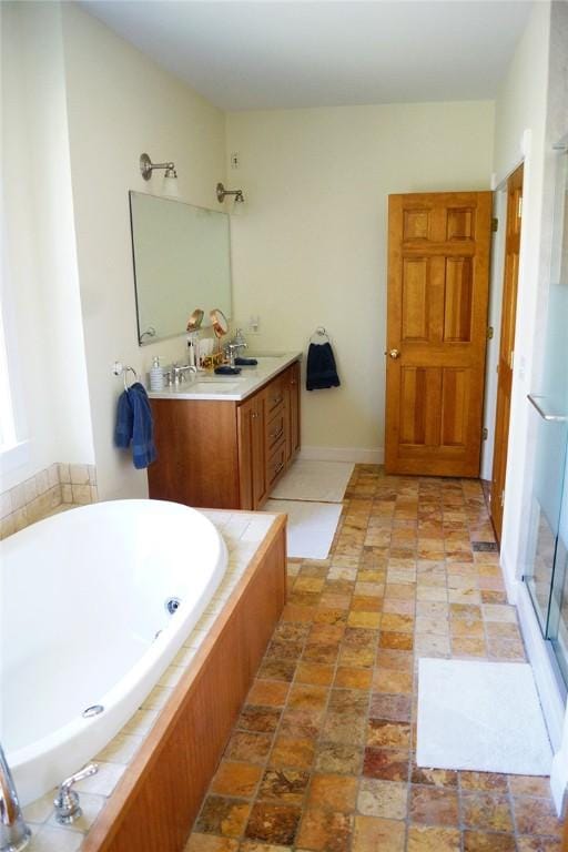 bathroom with double vanity, a sink, a bath, and a stall shower