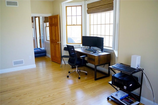 office space with baseboards, wood finished floors, and visible vents