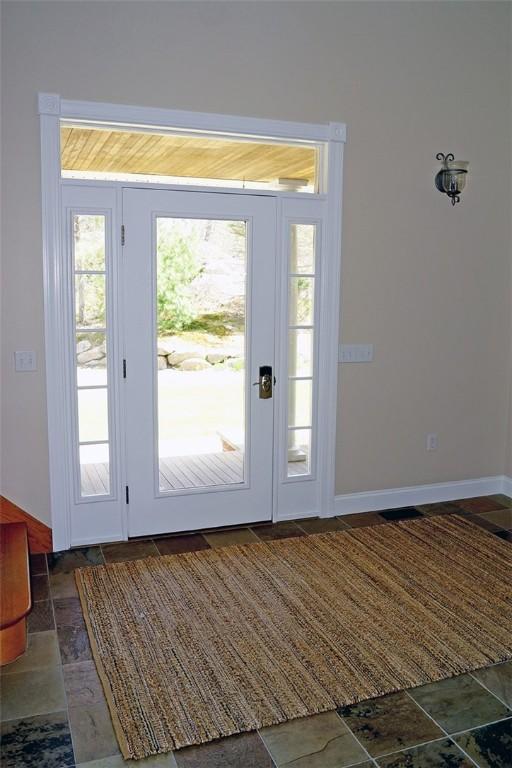 entryway with baseboards and stone finish floor