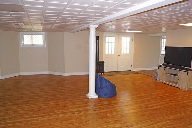 below grade area with baseboards, a wood stove, and wood finished floors