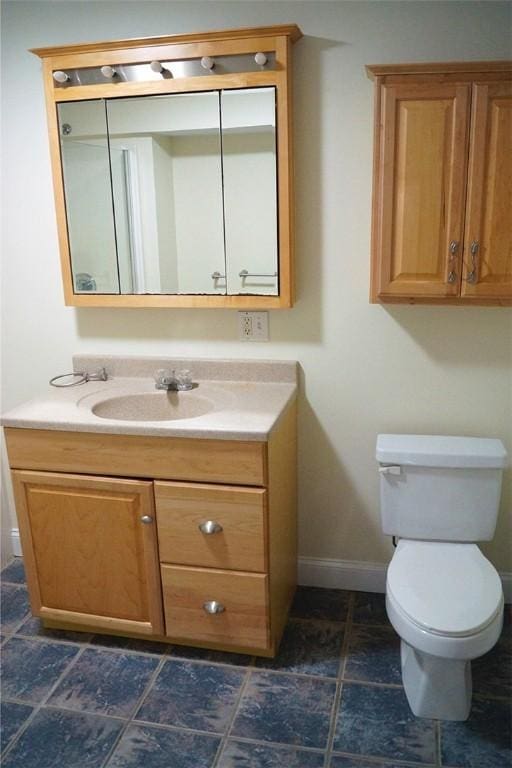 bathroom featuring toilet, baseboards, and vanity