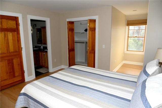 bedroom featuring connected bathroom, a walk in closet, light wood-style floors, baseboards, and a closet