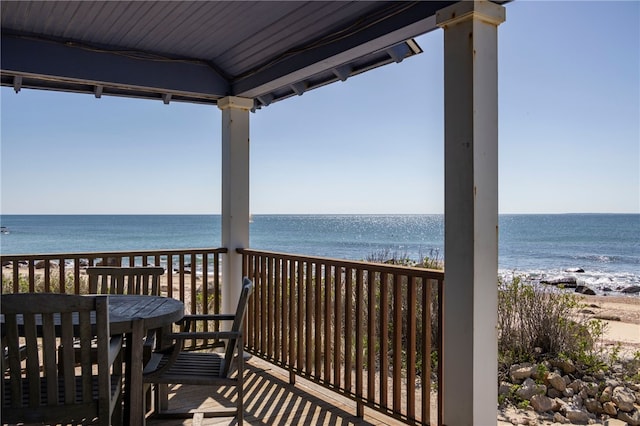 balcony with a beach view, a water view, and outdoor dining space