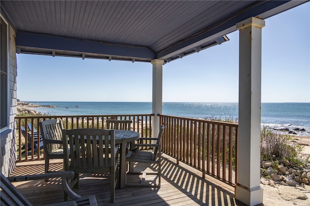 deck featuring a view of the beach, outdoor dining area, and a water view