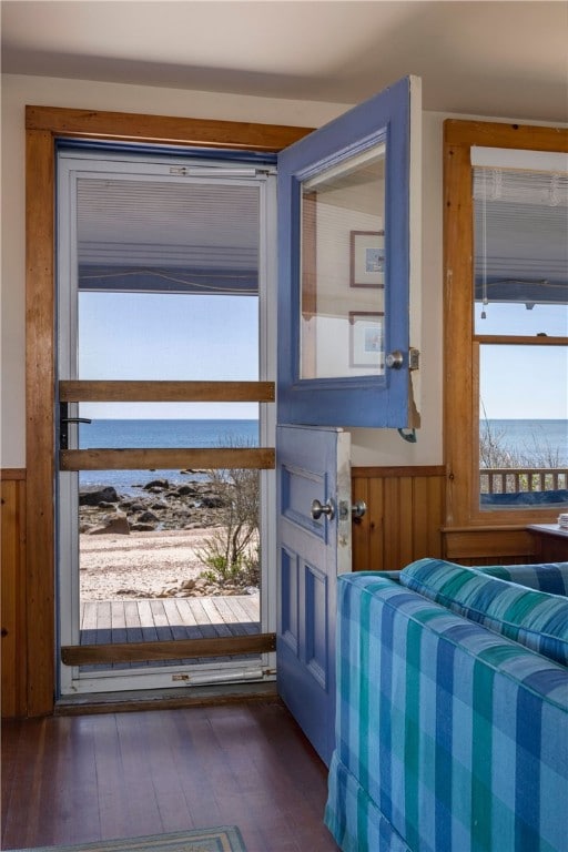 doorway to outside featuring a wainscoted wall, wood-type flooring, a water view, and wood walls