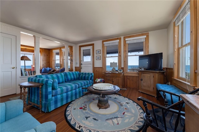 living area with a wainscoted wall, decorative columns, and wood finished floors