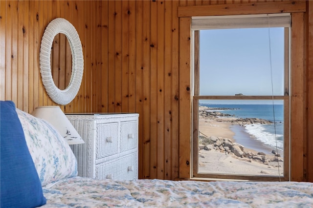 bedroom featuring a beach view, a water view, and wooden walls
