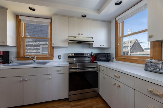 kitchen featuring under cabinet range hood, electric range, a sink, and light countertops