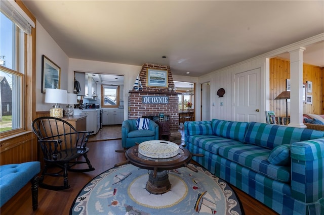 living area with wood walls, decorative columns, wood finished floors, and a fireplace