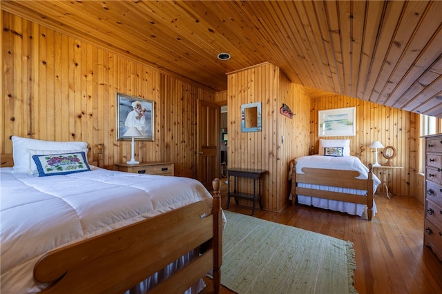 bedroom with wooden walls, lofted ceiling, wooden ceiling, and hardwood / wood-style flooring