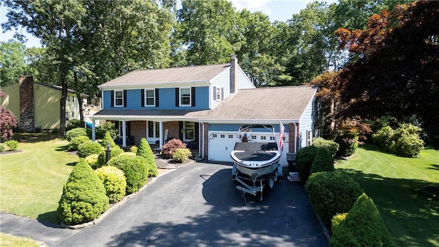 view of front of property with covered porch, driveway, a front lawn, and a garage