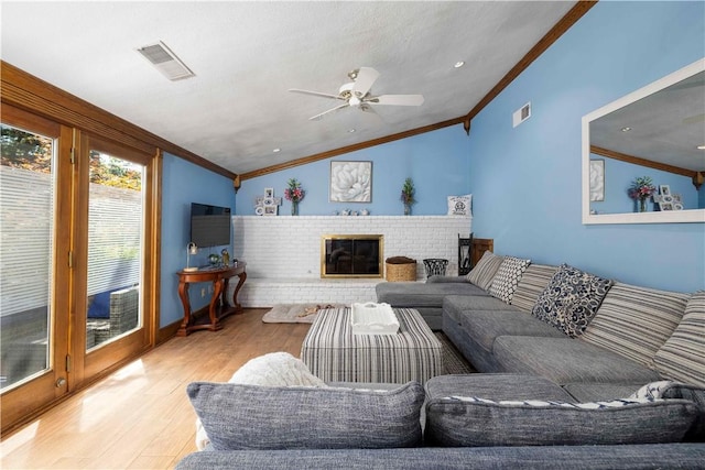 living area featuring crown molding, wood finished floors, vaulted ceiling, and visible vents