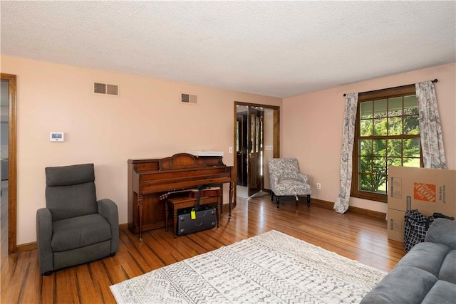 living area with baseboards, wood finished floors, and visible vents
