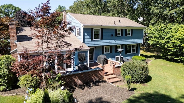 exterior space with a lawn, roof with shingles, and a chimney