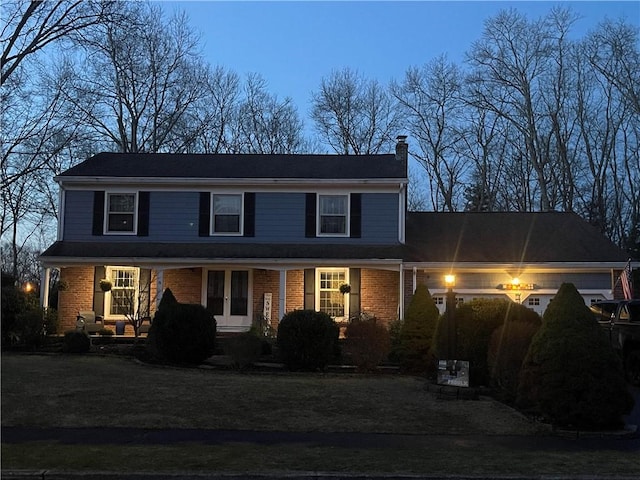 traditional-style house featuring a chimney and brick siding