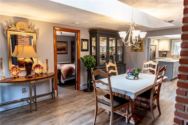 dining area with baseboard heating, a baseboard heating unit, light wood-type flooring, and a notable chandelier