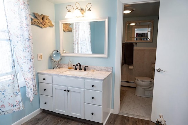 bathroom featuring wood finished floors, toilet, baseboard heating, and vanity