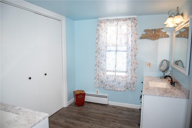 bathroom with baseboard heating, wood finished floors, vanity, baseboards, and a notable chandelier