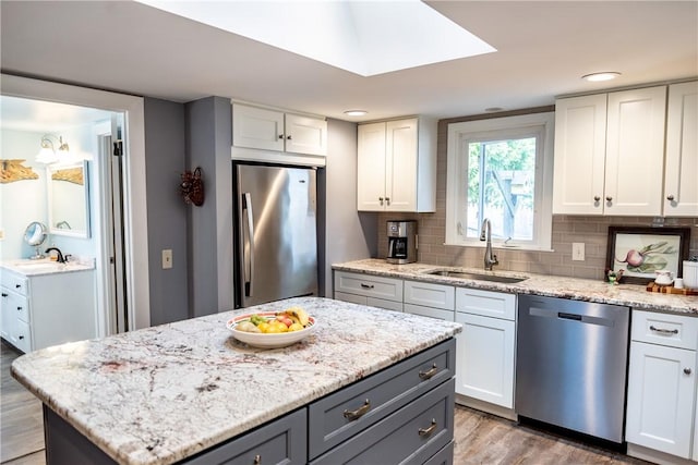 kitchen featuring a sink, wood finished floors, white cabinets, and stainless steel appliances