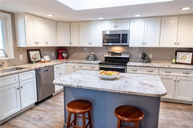kitchen with white cabinets, a kitchen breakfast bar, appliances with stainless steel finishes, and a sink