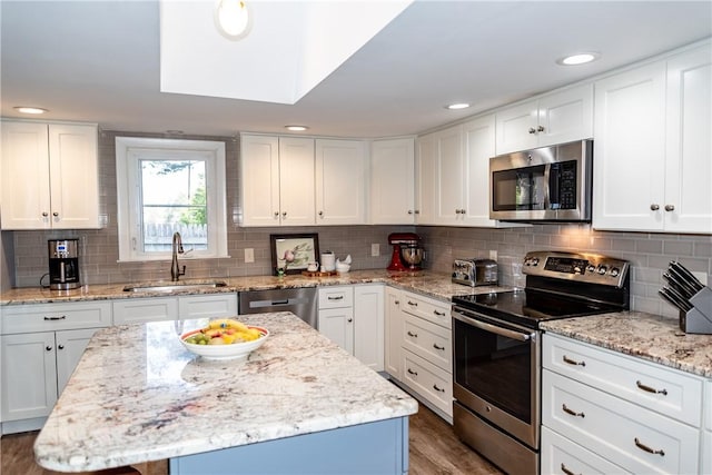 kitchen featuring stainless steel appliances, white cabinetry, a sink, and tasteful backsplash