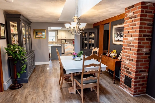 dining room with baseboards, a baseboard heating unit, wood finished floors, and a notable chandelier