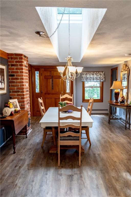 dining area with a baseboard heating unit, wood finished floors, and a chandelier