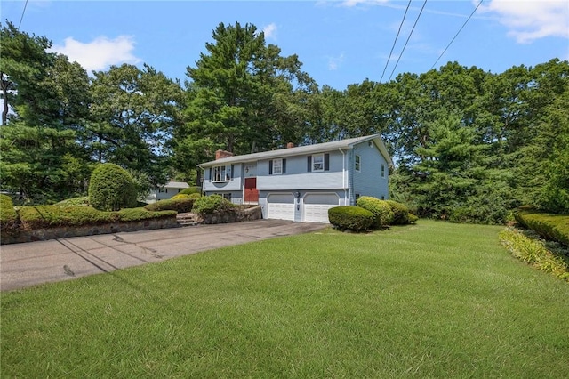 49 Magnolia Ln, Coventry, RI 02816 - split foyer home with concrete driveway, a chimney, an attached garage, and a front lawn