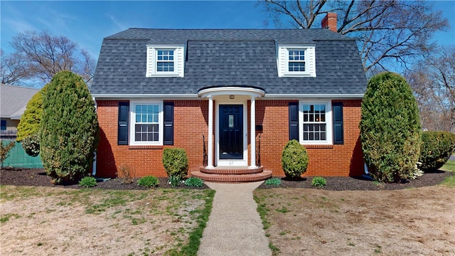 view of front of home with brick siding, a shingled roof, and a chimney