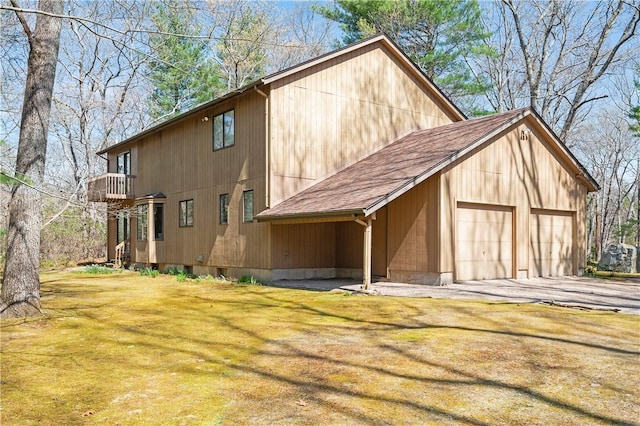 exterior space featuring a shingled roof, a balcony, a front yard, and a garage