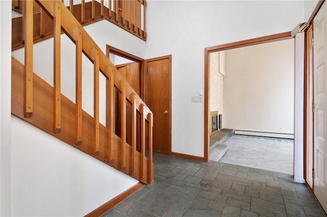 staircase featuring baseboards, baseboard heating, and stone tile floors