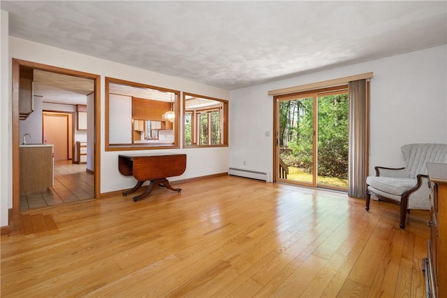interior space with baseboards, a baseboard heating unit, and light wood-type flooring