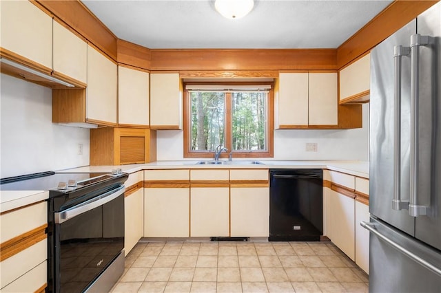 kitchen with light countertops, cream cabinets, a sink, light tile patterned floors, and stainless steel appliances