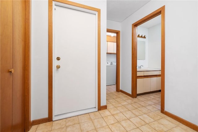 hall featuring baseboards, washing machine and dryer, and a sink