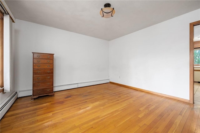 unfurnished room featuring baseboards, a baseboard heating unit, light wood finished floors, and a baseboard radiator