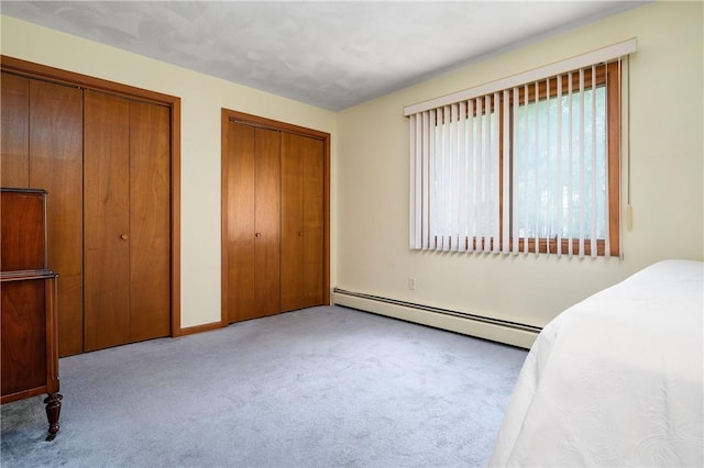 bedroom featuring baseboards, a baseboard radiator, two closets, and carpet flooring